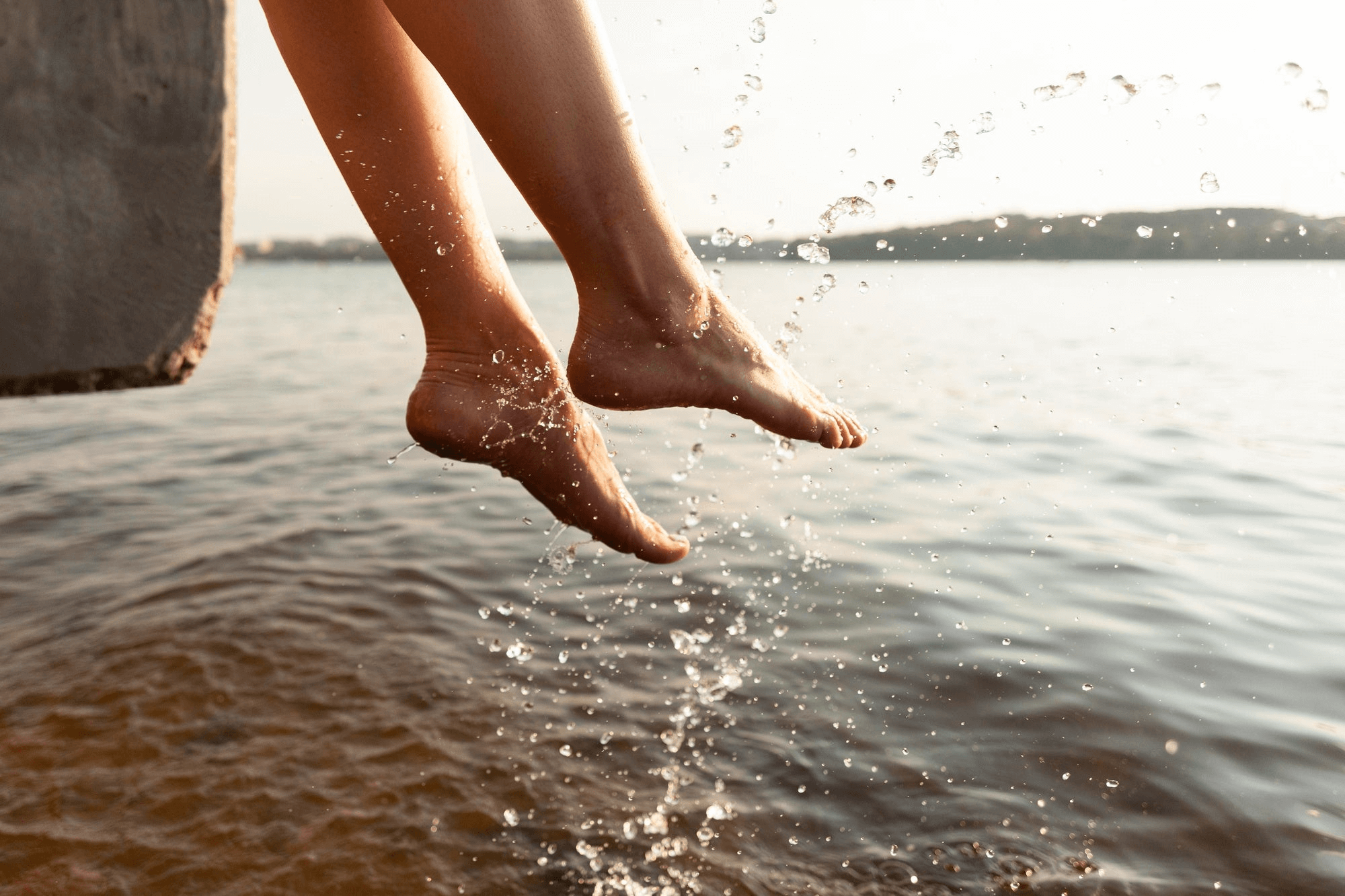 Feet dangling from rock, splashing in lake