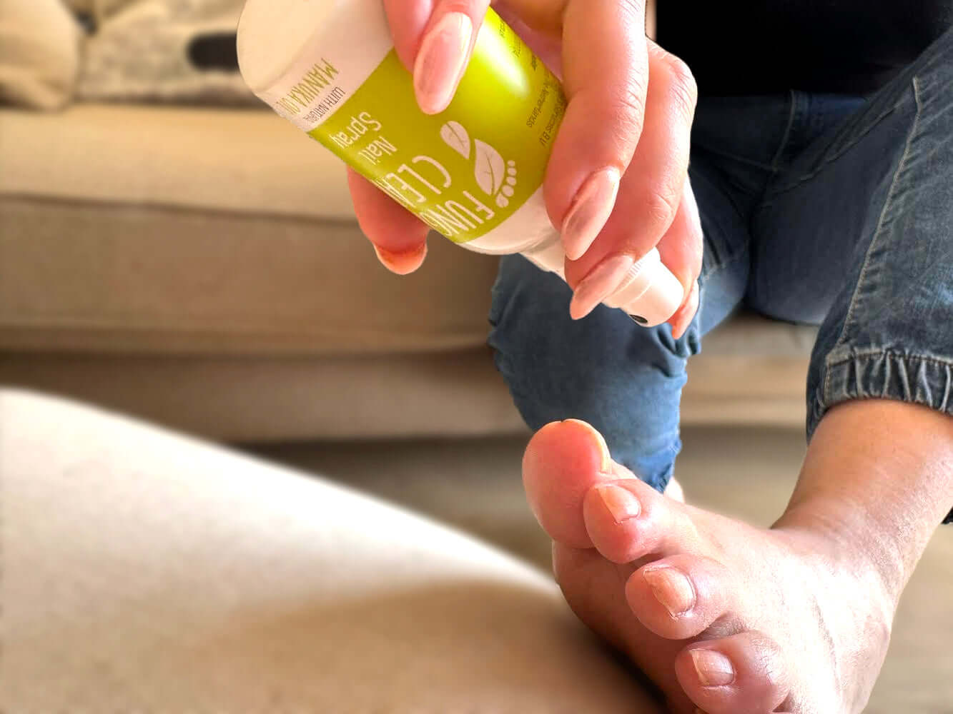 Person treating nail fungus using upside down spray in living room